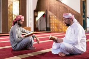 two muslim people in mosque reading quran together concept of islamic education photo