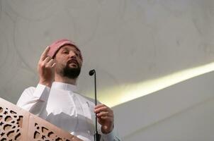 Muslims young arabic Imam has a speech on friday afternoon prayer in mosque. photo