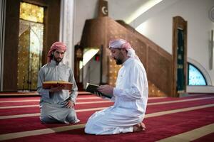 two muslim people in mosque reading quran together concept of islamic education photo