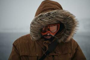 man at winter in stormy weather wearing warm  fur jacket photo