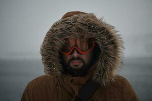 hombre en invierno en clima tormentoso con chaqueta de piel caliente foto