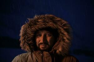 man at winter in stormy weather night  wearing warm  fur jacket photo