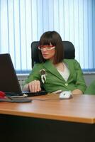 Smiling young businesswoman working on a laptop in the office. photo