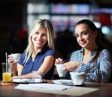 las chicas toman una taza de café en el restaurante foto