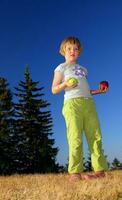 happy girl throwing apple outside photo