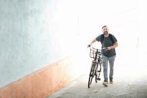 hipster man with a backpack pushing a retro bicycle photo