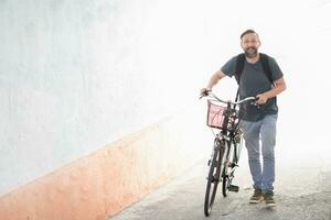 hipster man with a backpack pushing a retro bicycle photo