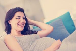pregnant woman sitting on sofa at home photo