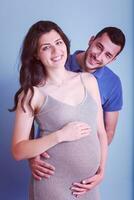 pregnant couple  isolated over blue background photo