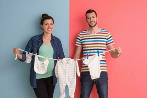 young couple holding baby bodysuits photo