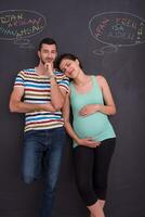pregnant couple writing on a black chalkboard photo