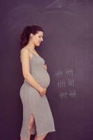 Portrait of pregnant woman in front of black chalkboard photo