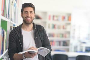 portrait of student while reading book  in school library photo