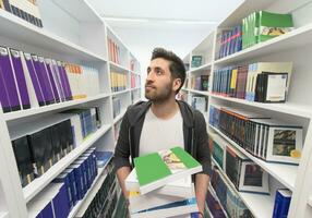 Student holding lot of books in school library photo