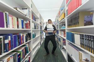 Student holding lot of books in school library photo