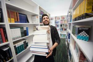 Student holding lot of books in school library photo