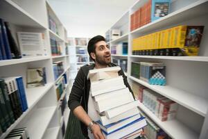 Student holding lot of books in school library photo