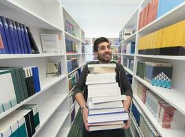 estudiante con muchos libros en la biblioteca escolar foto