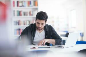 student in school library using laptop for research photo