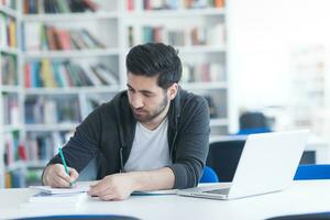 student in school library using laptop for research photo