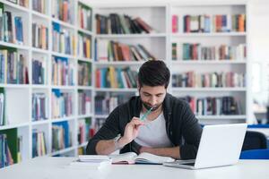 estudiante en la biblioteca escolar usando una computadora portátil para investigar foto