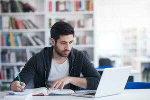 estudiante en la biblioteca escolar usando una computadora portátil para investigar foto