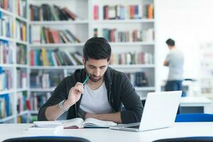 estudiante en la biblioteca escolar usando una computadora portátil para investigar foto