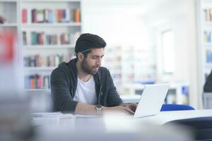 student in school library using laptop for research photo