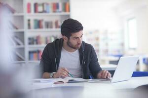 student in school library using laptop for research photo