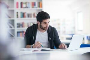 estudiante en la biblioteca escolar usando una computadora portátil para investigar foto