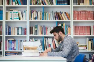 portrait of student while reading book  in school library photo