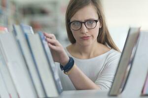 portrait of famale student selecting book to read in library photo