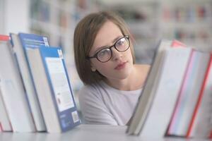 portrait of famale student selecting book to read in library photo