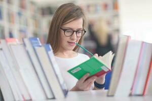 retrato de estudiante famale seleccionando un libro para leer en la biblioteca foto