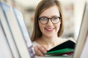 portrait of famale student selecting book to read in library photo