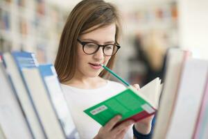 portrait of famale student selecting book to read in library photo