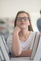 portrait of famale student selecting book to read in library photo