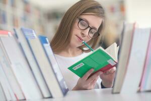 portrait of famale student selecting book to read in library photo