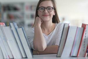 portrait of famale student selecting book to read in library photo
