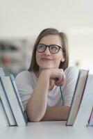 portrait of famale student selecting book to read in library photo