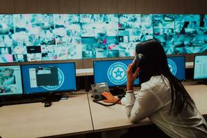 Female security operator working in a data system control room offices Technical Operator Working at workstation with multiple displays, security guard working on multiple monitors photo