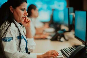 Female security guard operator talking on the phone while working at workstation with multiple displays Security guards working on multiple monitors photo