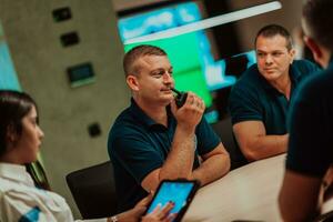 Group of security guards sitting and having briefing In the system control room They're working in security data center surrounded by multiple Screens photo