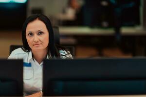 Female security operator working in a data system control room offices Technical Operator Working at workstation with multiple displays, security guard working on multiple monitors photo