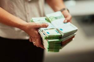 Bank employees holding a pile of paper banknotes while sorting and counting inside bank vault. Large amounts of money in the bank photo