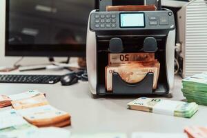 ordenado billetes metido en el mesa después eso es contado en el electrónico dinero contando máquina foto