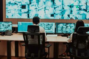 Group of Security data center operators working in a CCTV monitoring room looking on multiple monitors Officers Monitoring Multiple Screens for Suspicious Activities Team working on the System Contr photo