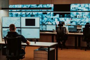 Male security operator working in a data system control room offices Technical Operator Working at workstation with multiple displays, security guard working on multiple monitors Male computer opera photo