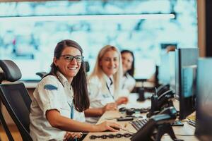 Group of female security operators working in a data system control room Technical Operators Working at workstation with multiple displays, security guards working on multiple monitors in surveillan photo