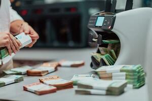 banco empleados utilizando dinero contando máquina mientras clasificación y contando papel billetes dentro banco bóveda. grande cantidades de dinero en el banco foto